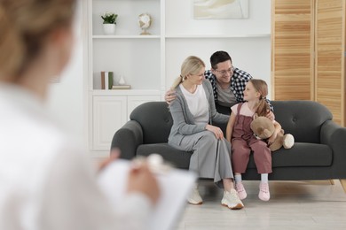 Photo of Happy family having consultation with psychologist in office, selective focus