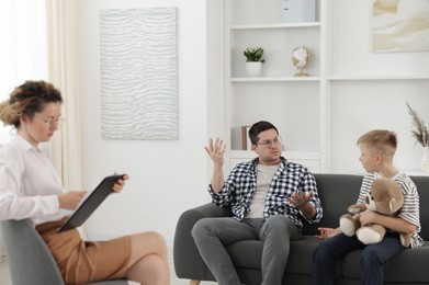 Photo of Father and son having consultation with psychologist in office, selective focus