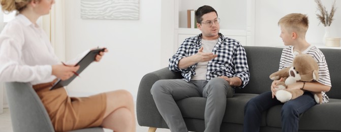Photo of Father and son having consultation with psychologist in office, selective focus