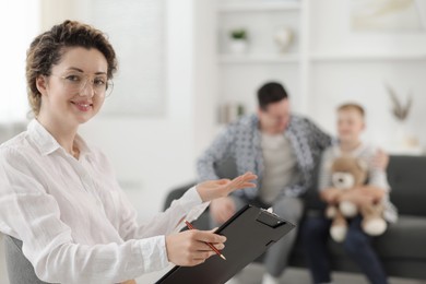 Photo of Father and son having consultation with smiling psychologist in office, selective focus