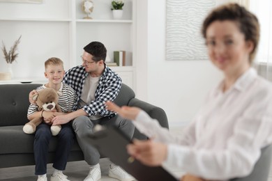 Photo of Happy father and son having consultation with psychologist in office, selective focus