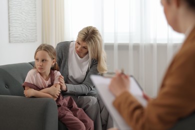 Photo of Mother and daughter having consultation with psychologist in office, selective focus