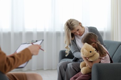 Photo of Mother and daughter having consultation with psychologist in office, selective focus