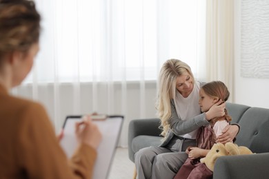 Photo of Mother and daughter having consultation with psychologist in office, selective focus