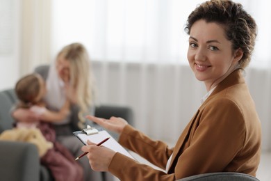 Photo of Mother and daughter having consultation with smiling psychologist in office, selective focus