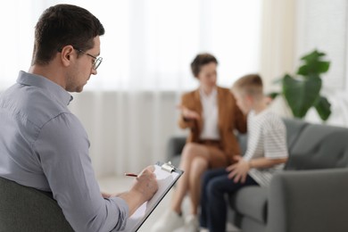 Photo of Mother and son having consultation with psychologist in office, selective focus
