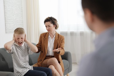 Photo of Mother and son having consultation with psychologist in office, selective focus