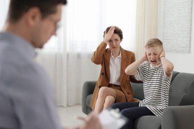 Photo of Mother and son having consultation with psychologist in office, selective focus