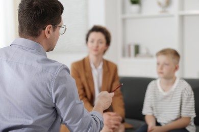 Photo of Mother and son having consultation with psychologist in office, selective focus