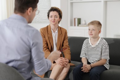 Photo of Mother and son having consultation with psychologist in office, selective focus