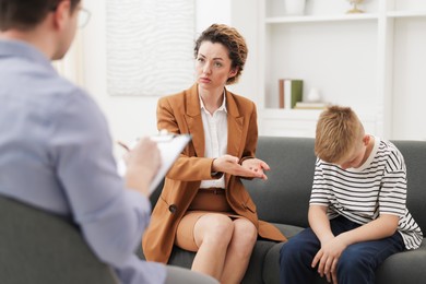 Photo of Mother and son having consultation with psychologist in office, selective focus
