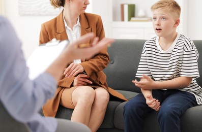Photo of Mother and son having consultation with psychologist in office, selective focus