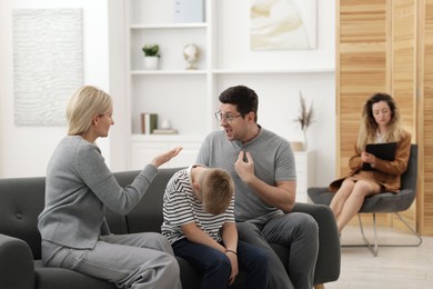 Photo of Family arguing during consultation with psychologist in office, selective focus