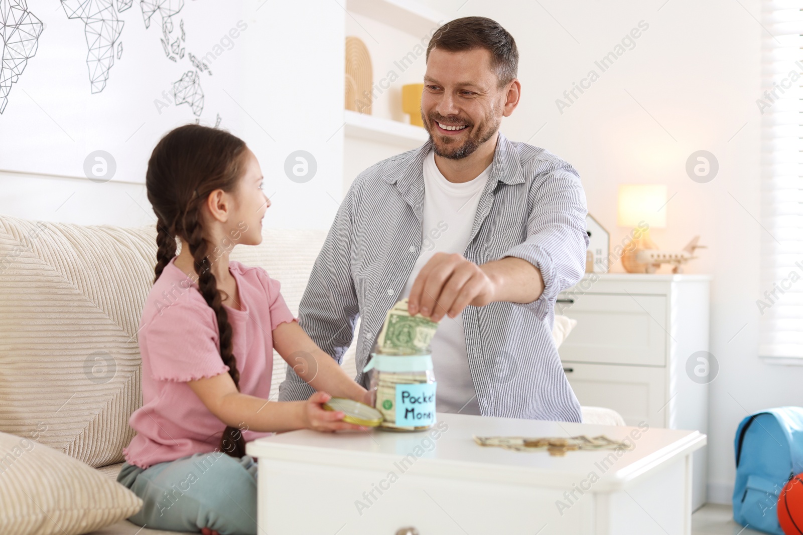 Father giving his daughter pocket money at table indoors Photo of Father giving his daughter pocket money at table indoors