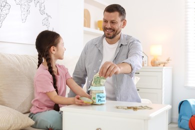Photo of Father giving his daughter pocket money at table indoors