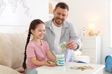 Photo of Father giving his daughter pocket money at table indoors