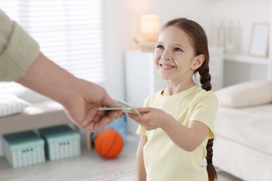 Photo of Father giving his daughter pocket money at home, closeup