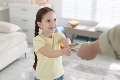 Photo of Father giving his daughter pocket money at home, closeup