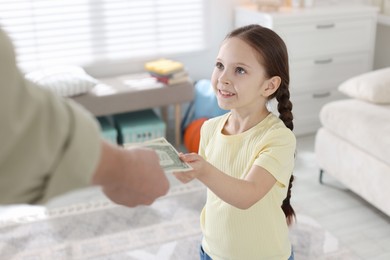 Photo of Father giving his daughter pocket money at home, closeup