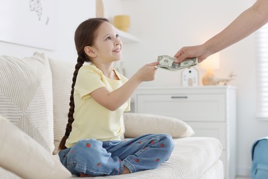 Photo of Mother giving her daughter pocket money on sofa at home, closeup