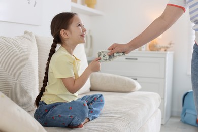 Photo of Mother giving her daughter pocket money on sofa at home, closeup