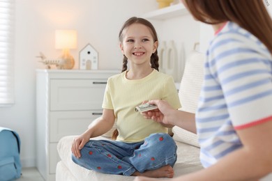 Photo of Mother giving her daughter pocket money on sofa at home, closeup