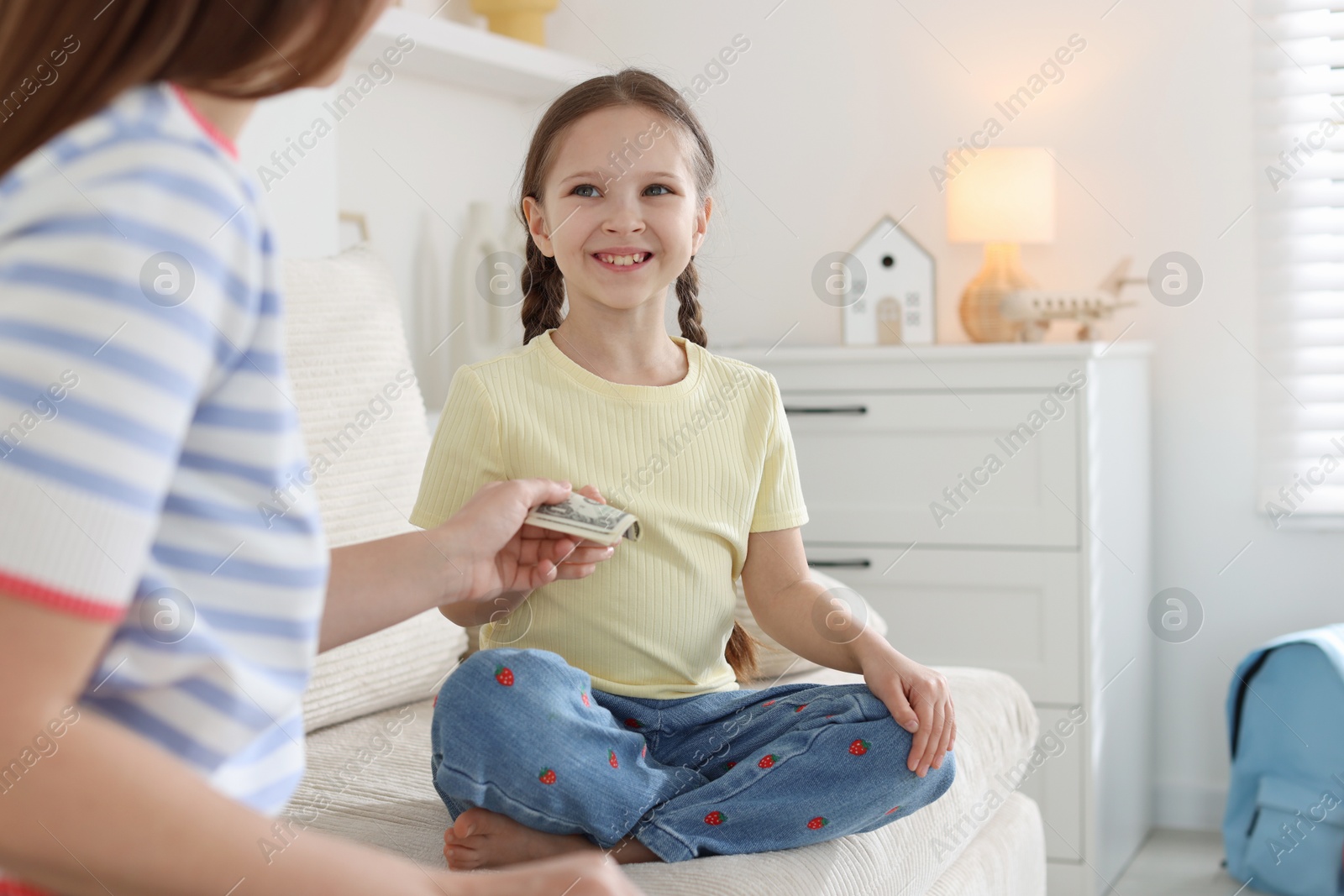 Mother giving her daughter pocket money on sofa at home, closeup Photo of Mother giving her daughter pocket money on sofa at home, closeup