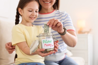 Photo of Mother giving her daughter pocket money on sofa at home, closeup