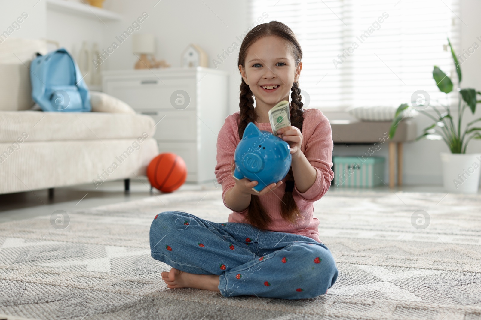 Girl with piggybank of pocket money at home Photo of Girl with piggybank of pocket money at home