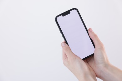 Photo of Woman holding smartphone with blank screen on white background, closeup. Mockup for design