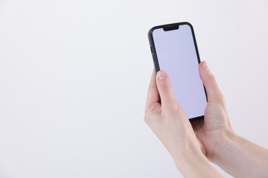 Photo of Woman holding smartphone with blank screen on white background, closeup. Mockup for design