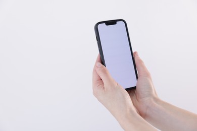 Photo of Woman holding smartphone with blank screen on white background, closeup. Mockup for design