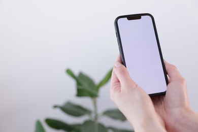 Photo of Woman holding smartphone with blank screen on blurred background, closeup. Mockup for design
