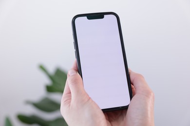 Photo of Woman holding smartphone with blank screen on blurred background, closeup. Mockup for design