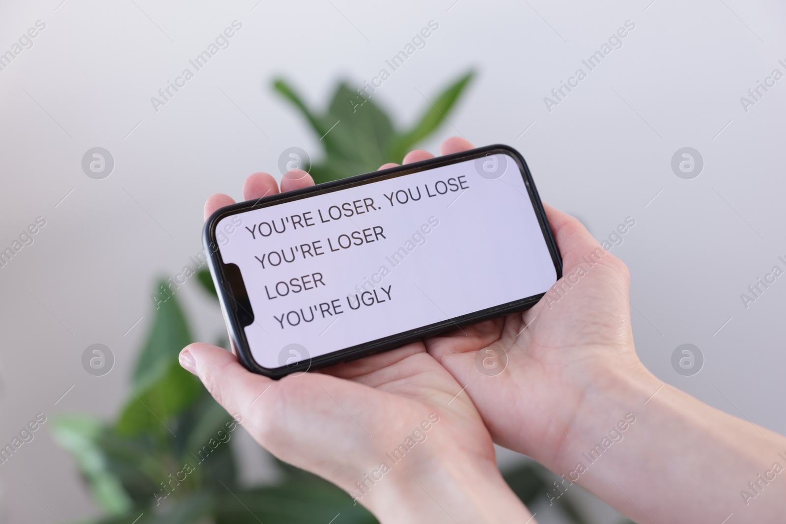 Cyber bullying. Woman holding smartphone with insults on blurred background, closeup Photo of Cyber bullying. Woman holding smartphone with insults on blurred background, closeup