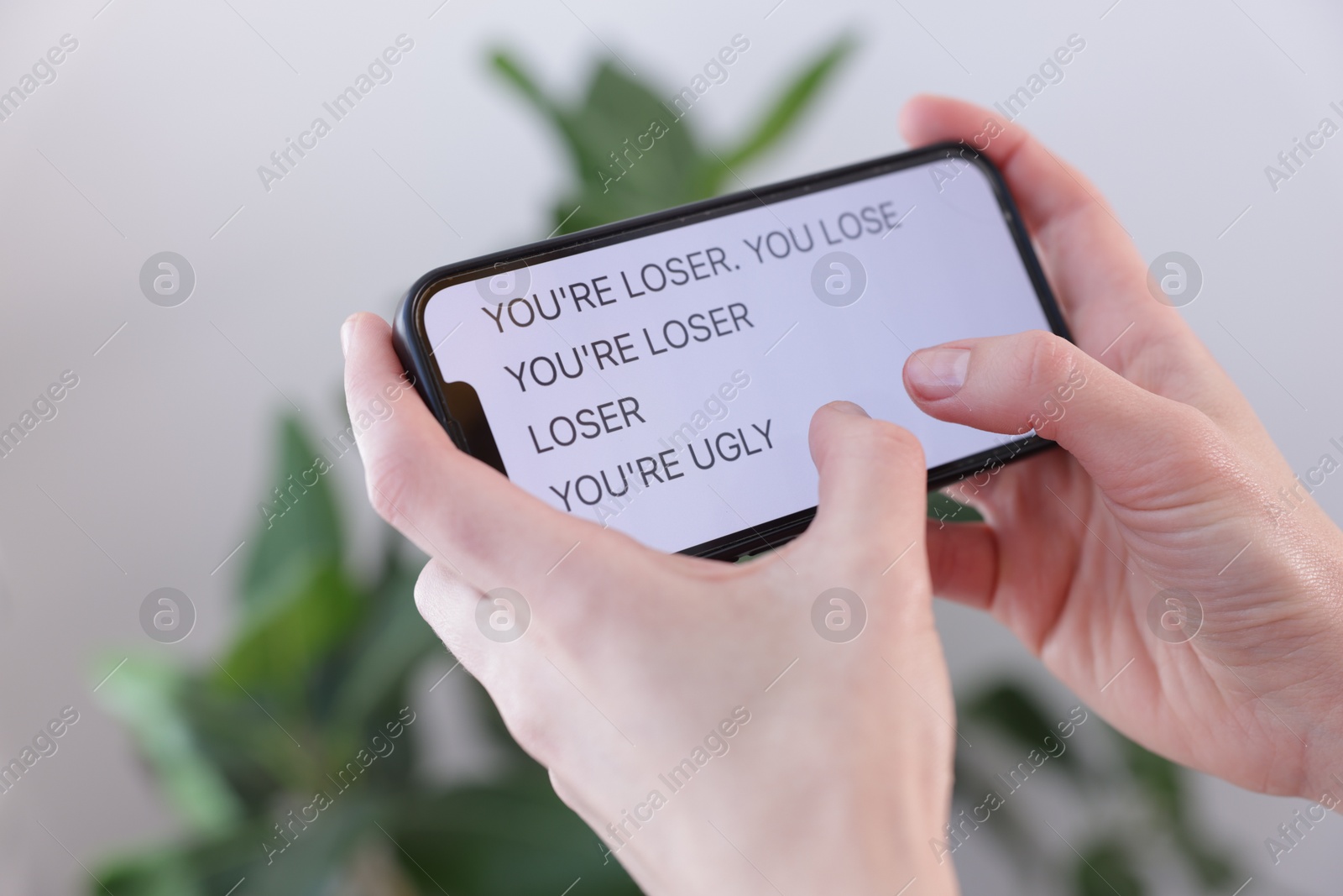 Cyber bullying. Woman holding smartphone with insults on blurred background, closeup Photo of Cyber bullying. Woman holding smartphone with insults on blurred background, closeup