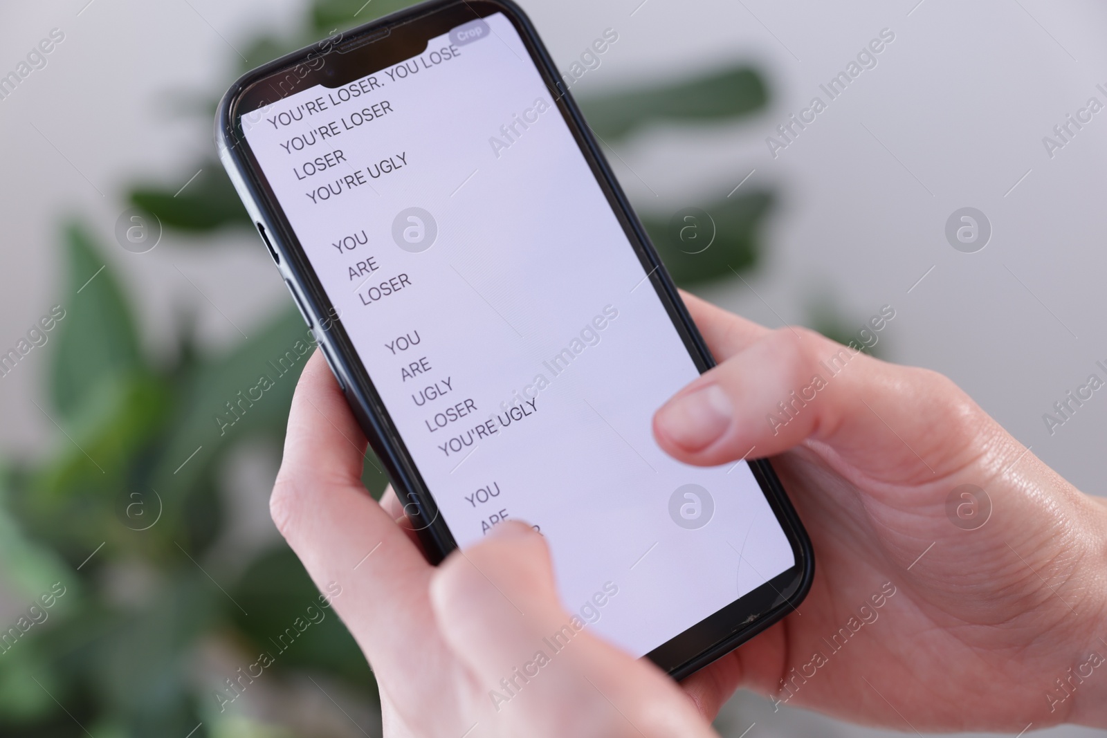 Cyber bullying. Woman holding smartphone with insults on blurred background, closeup Photo of Cyber bullying. Woman holding smartphone with insults on blurred background, closeup