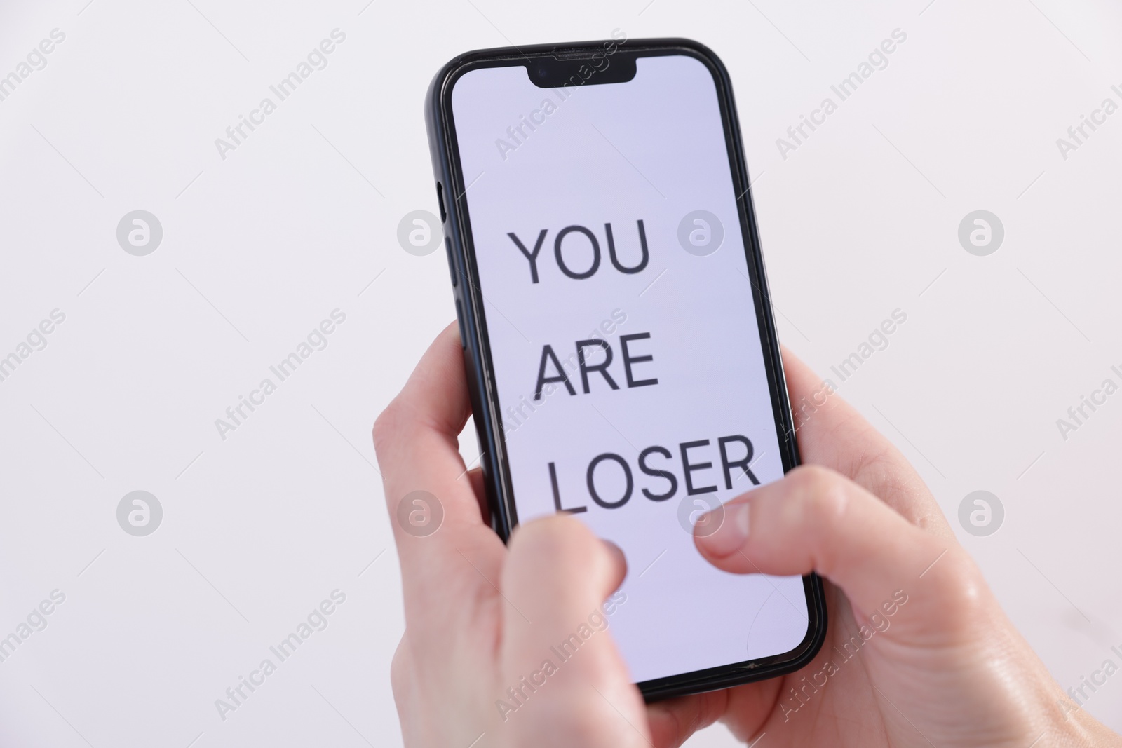 Photo of Cyber bullying. Woman holding smartphone with text You Are Loser on white background, closeup