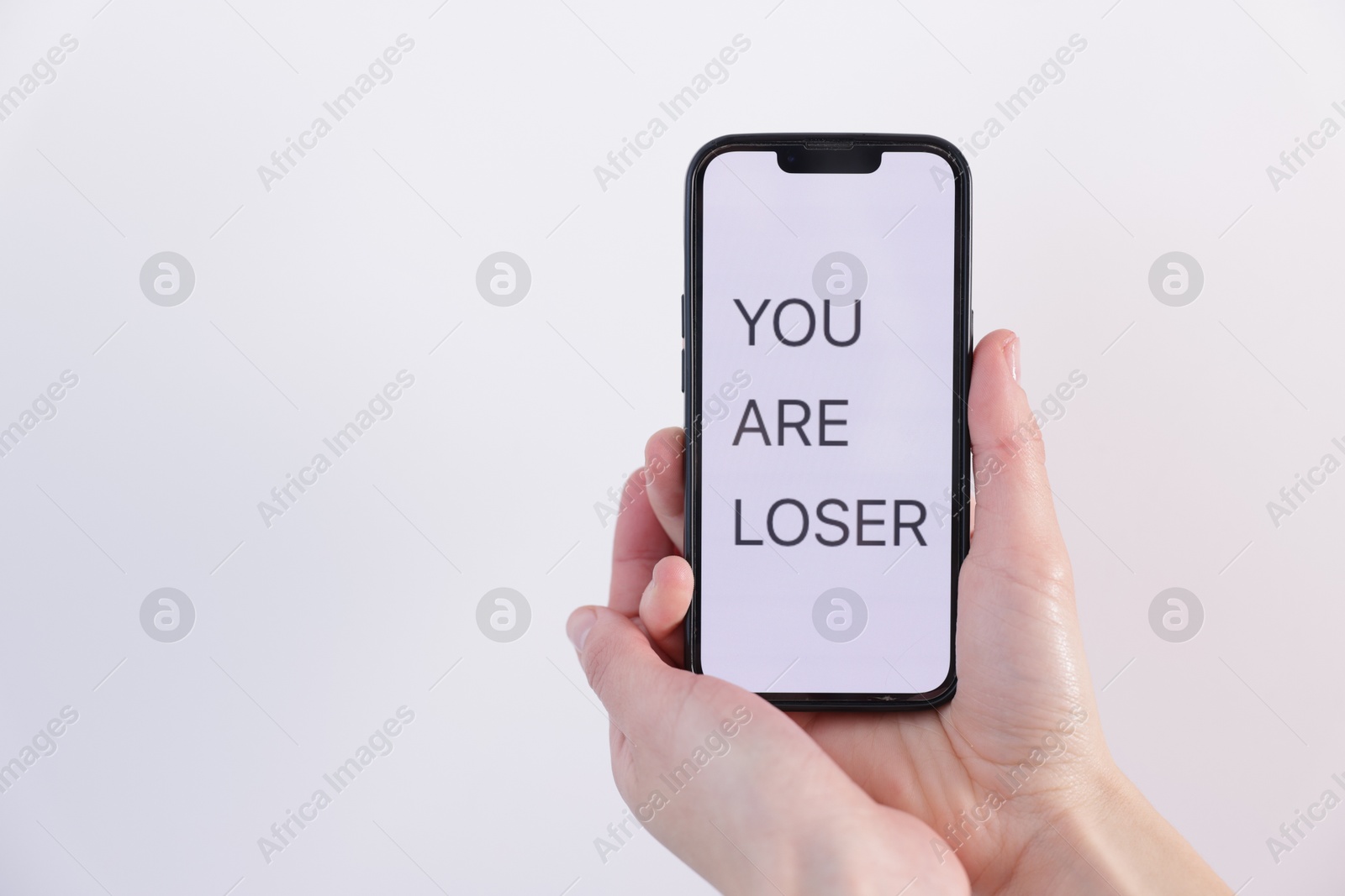 Cyber bullying. Woman holding smartphone with text You Are Loser on white background, closeup. Space for text Photo of Cyber bullying. Woman holding smartphone with text You Are Loser on white background, closeup. Space for text