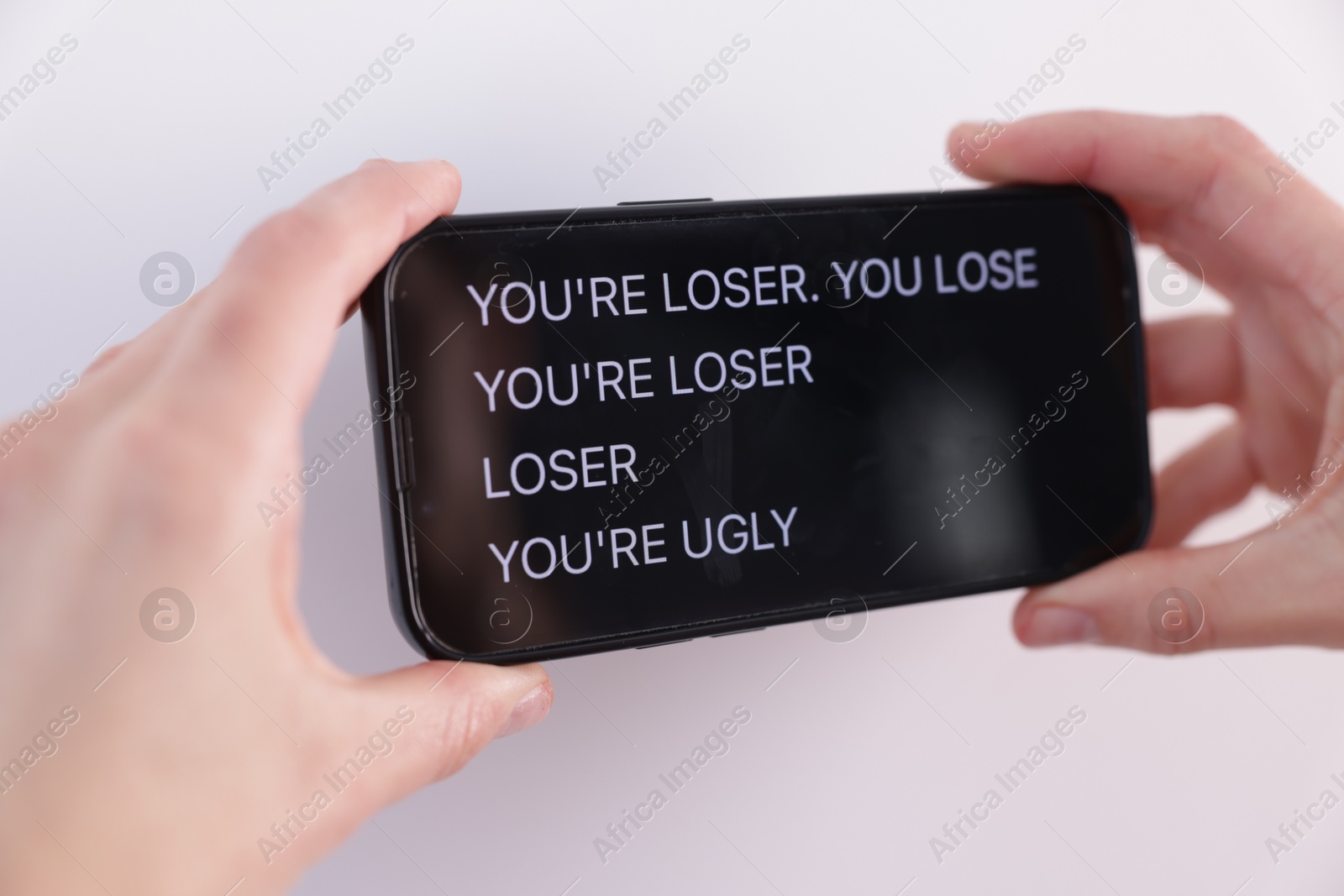 Cyber bullying. Woman holding smartphone with insults on white background, closeup Photo of Cyber bullying. Woman holding smartphone with insults on white background, closeup