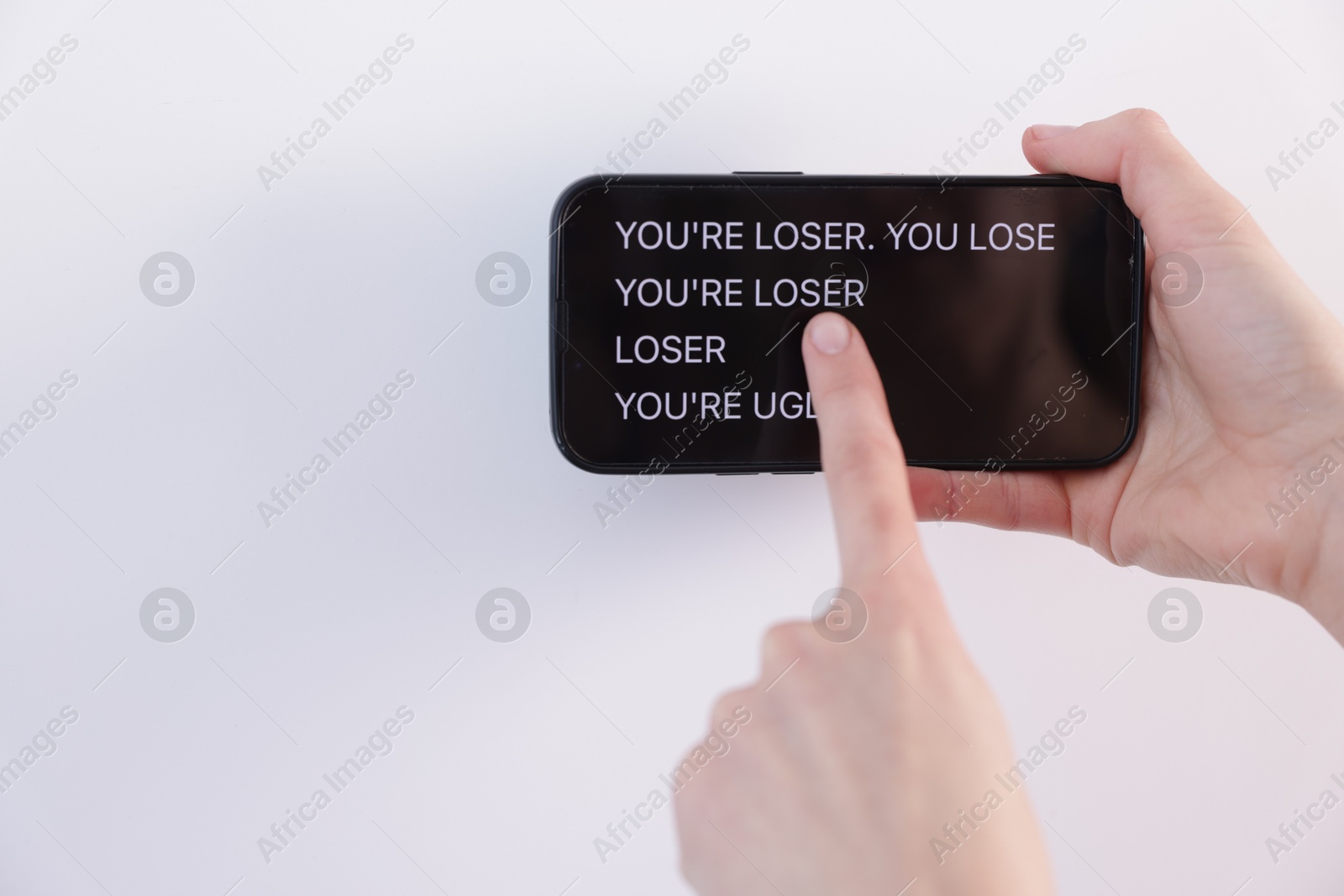 Cyber bullying. Woman holding smartphone with insults on white background, closeup. Space for text Photo of Cyber bullying. Woman holding smartphone with insults on white background, closeup. Space for text