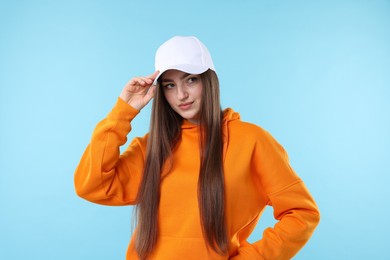 Photo of Portrait of beautiful woman in stylish baseball hat on light blue background