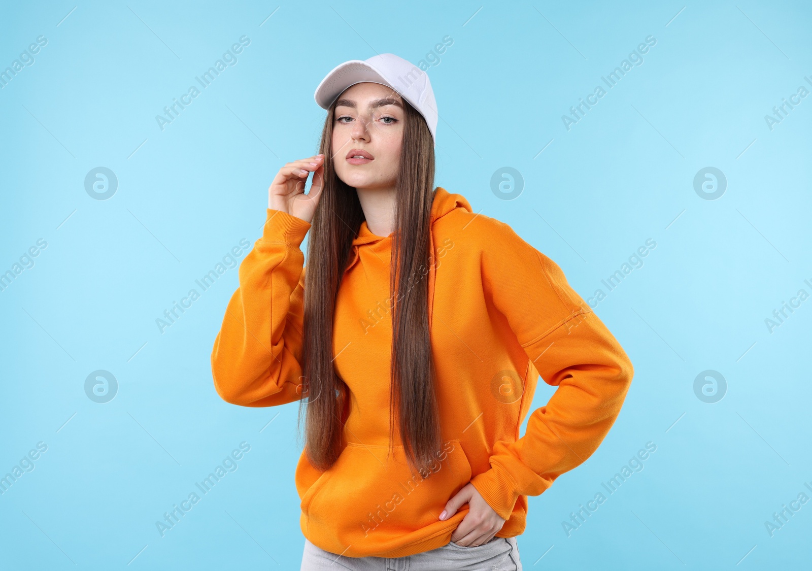 Portrait of beautiful woman in stylish baseball hat on light blue background Photo of Portrait of beautiful woman in stylish baseball hat on light blue background