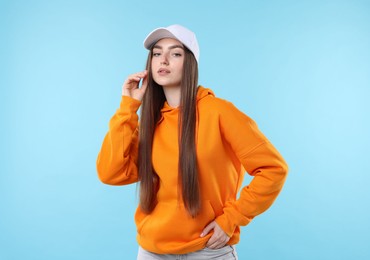 Photo of Portrait of beautiful woman in stylish baseball hat on light blue background