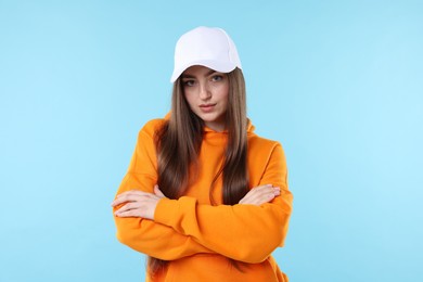 Photo of Portrait of beautiful woman in stylish baseball hat on light blue background