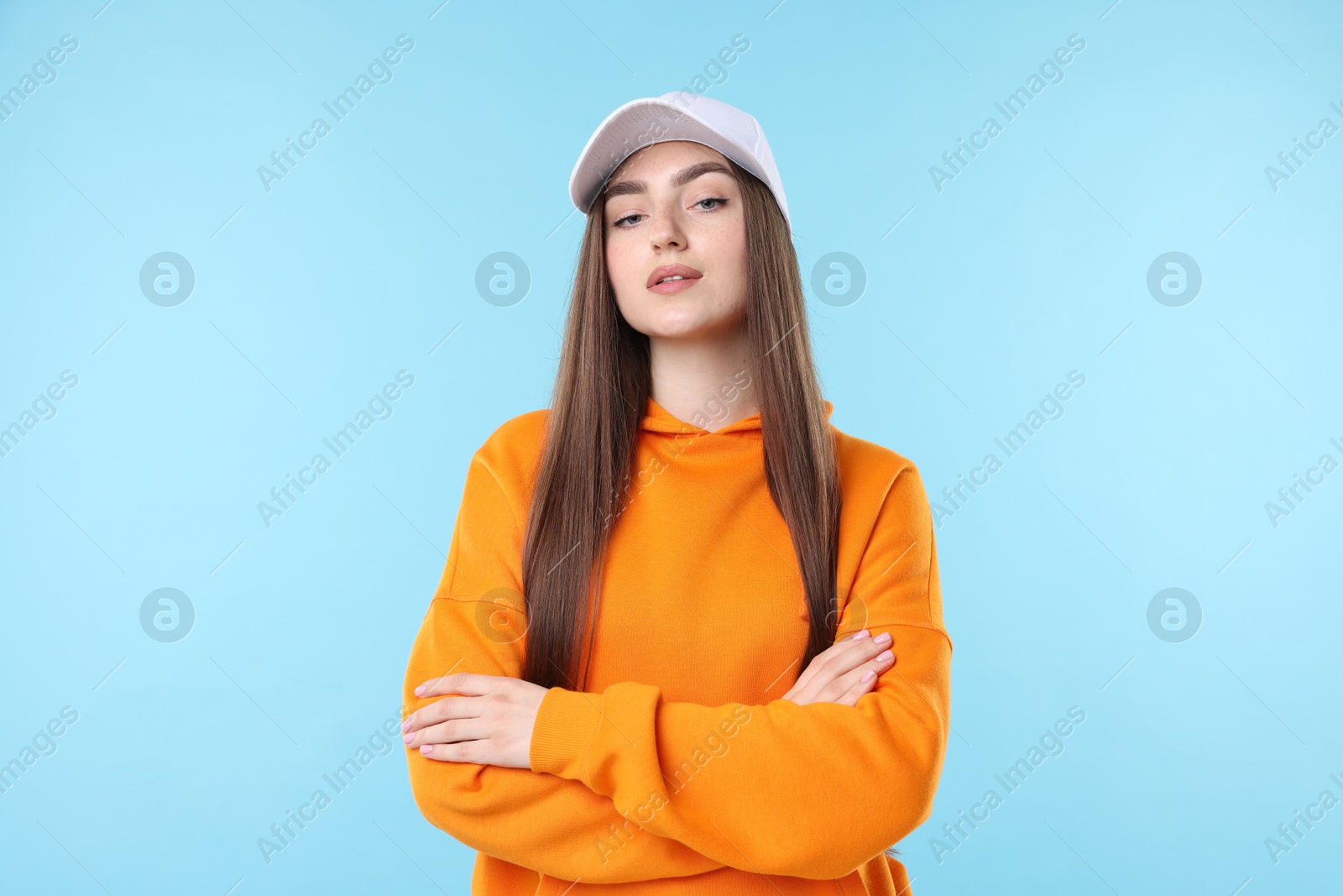 Portrait of beautiful woman in stylish baseball hat on light blue background Photo of Portrait of beautiful woman in stylish baseball hat on light blue background