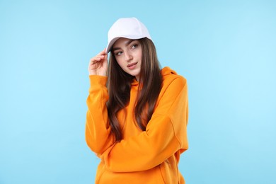 Photo of Portrait of beautiful woman in stylish baseball hat on light blue background