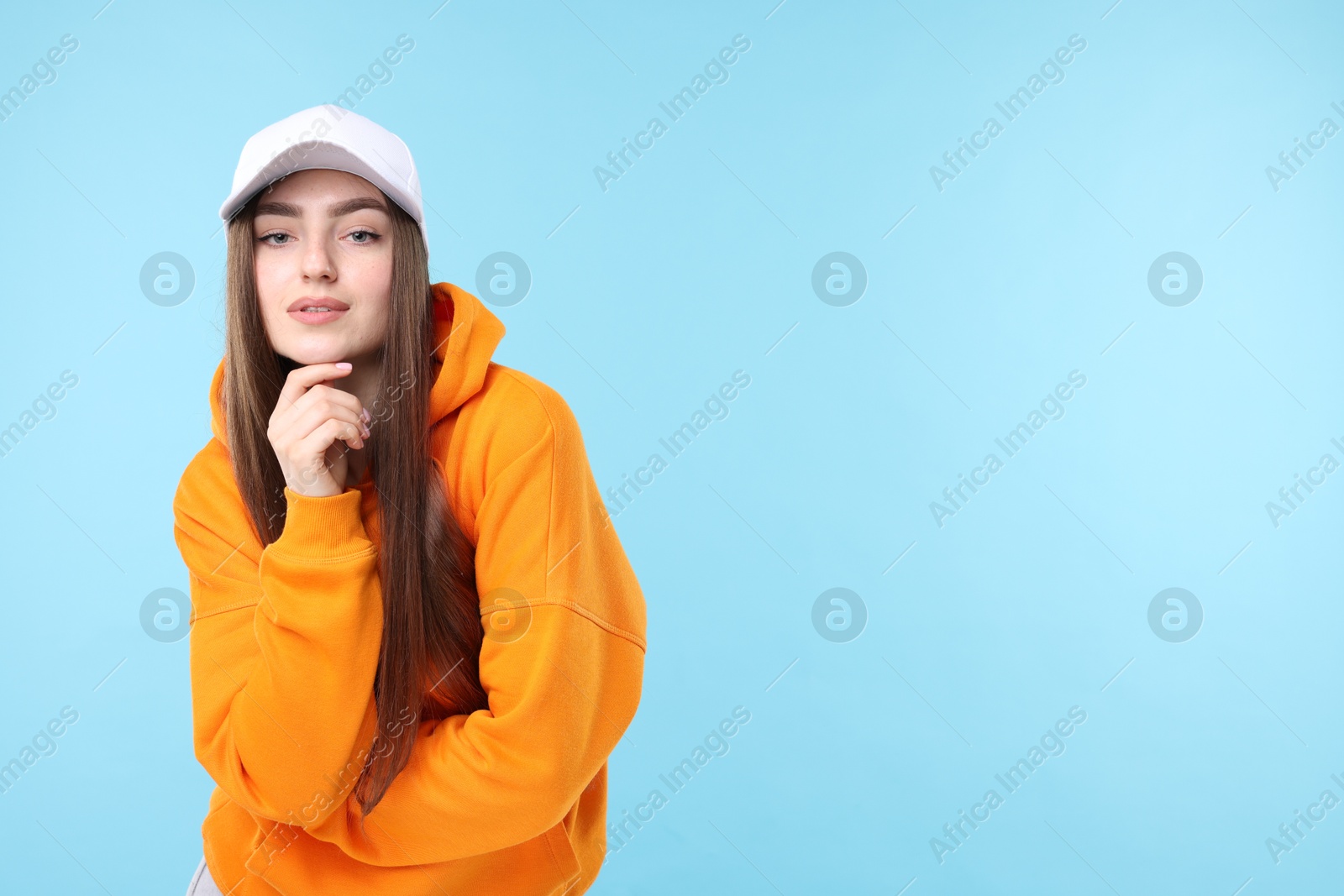 Portrait of beautiful woman in stylish baseball hat on light blue background. Space for text Photo of Portrait of beautiful woman in stylish baseball hat on light blue background. Space for text