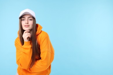 Photo of Portrait of beautiful woman in stylish baseball hat on light blue background. Space for text