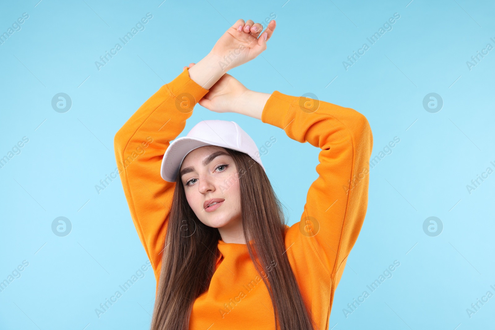 Portrait of beautiful woman in stylish baseball hat on light blue background Photo of Portrait of beautiful woman in stylish baseball hat on light blue background